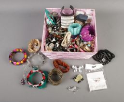 A box of assorted costume jewellery to include bangles, brooches, pin badges, etc.