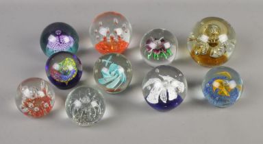 A collection of ten glass paperweights to include floral and bubble examples.