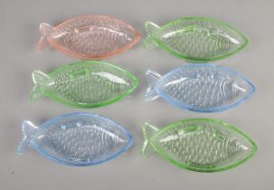 A set of six dishes in the form of fish with varying colours.