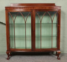 A mahogany display cabinet raised on ball and claw feet.