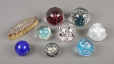 A collection of eight glass paperweights in varying sizes including a Caithness Congratulations