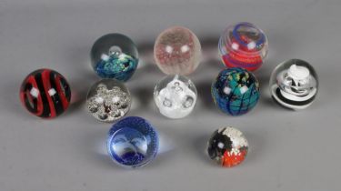 A collection of ten glass paperweights of varying sizes to include Caithness Dolphin and examples