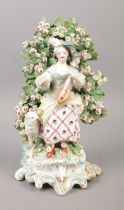 An 18th century Derby porcelain figure modelled as a loot player with bocage surround. 20cm.