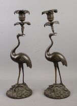 A large pair of bronze figural candlesticks formed as storks raised on mounds of vegetation and