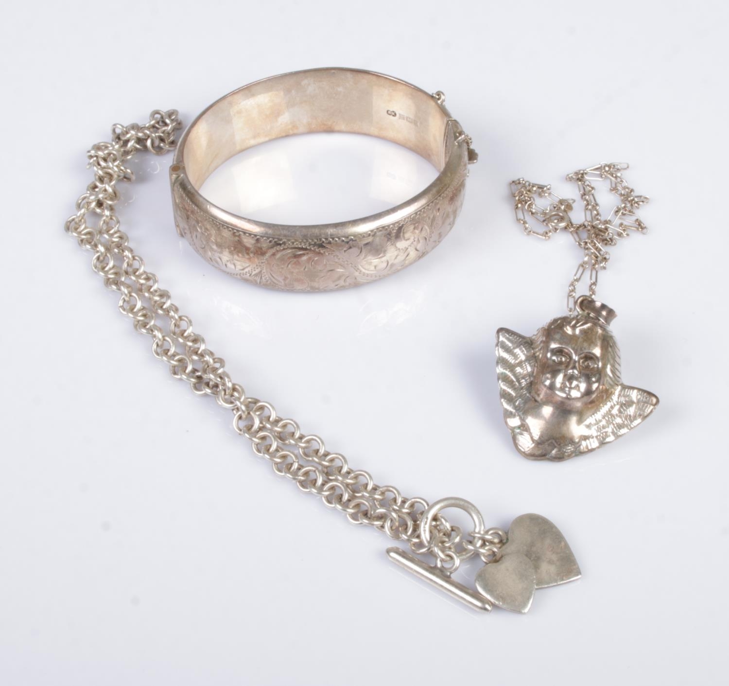 A collection of silver jewellery to include bangle, cherub pendant on chain and heart pendant on