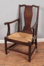 A Georgian oak elbow arm chair featuring vase splat vase and woven rush seat.