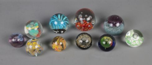 A collection of ten glass paperweights in varying sizes to include Caithness Fountain and Mdina