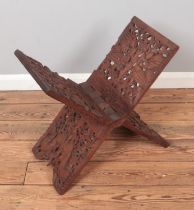 An Indian carved hardwood folding stand, possibly scriptures stand. Featuring depictions of