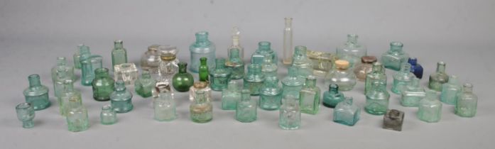 A large collection of mainly glass inkwells, including circular and hinged top examples.