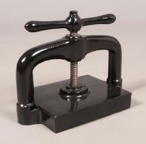 A black painted cast iron hand crank book press. Base platform measurements 23cm x 28cm.