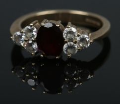 A 9ct ring set with large central garnet flanked by six cubic zirconia stones. Size OÂ½, 3.6g.