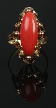 A 14ct gold cabochon coral ring with scrollwork border. Coral length approximately 2cm. Size Q. 3.