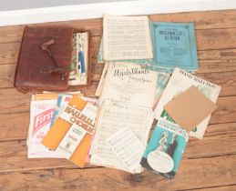 A vintage leather music bag with contents of assorted sheet and carol music scores. Examples include