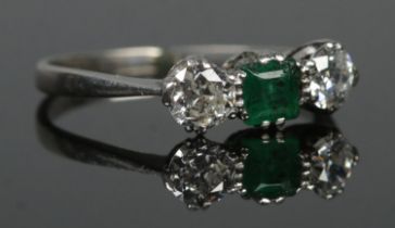 An Art Deco platinum, diamond and emerald three stone ring. Size M. 2.57g. Slight scuff to emerald