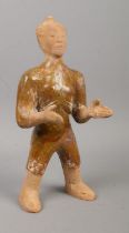 A partially glazed Chinese terracotta tomb figure formed as a servant with outstretched arms.