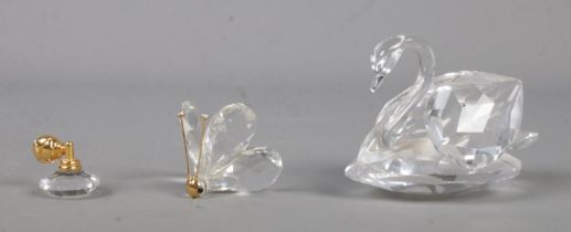 Three Swarovski crystal figures formed as a swan, butterfly and atomizer bottle.