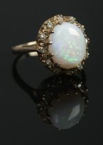 A 9ct gold dress ring set with a large cabochon opal stone within a diamond halo surround. Hallmarks