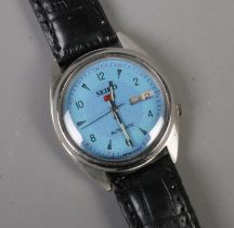 A men's Seiko 5 automatic wristwatch featuring blue face, leather strap and day date display.