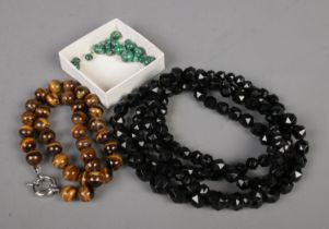 A long graduated, faceted Jet beaded necklace along with another tigers eye bead necklace and