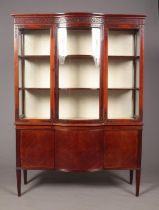 An Edwardian mahogany display cabinet raised on cupboard base and four tapering supports. Having