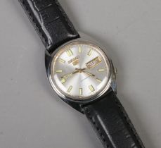 A men's Seiko 5 automatic wristwatch featuring leather strap, baton markers and day date display. In