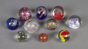 A collection of ten glass paperweights in varying sizes to include Caithness Champagne and