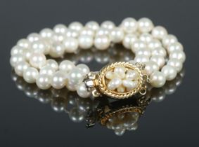 A triple strand pearl bracelet with yellow metal clasp 18cm unclasped.