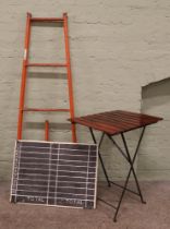 A folding table along with tubular steel platform ladders and a scoreboard.