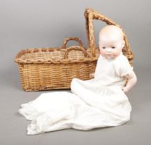 A Heubach Koppelsdorf bisque head doll, in wicker carry cot. Stamped 350 3/0 Germany to back. Height