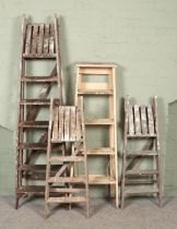 Four sets of vintage wooden stepladders.