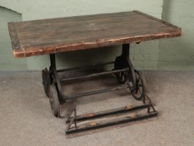 A slated pitch pine table, raised on cast iron slate wagon base. Featuring six-spoke wheels and