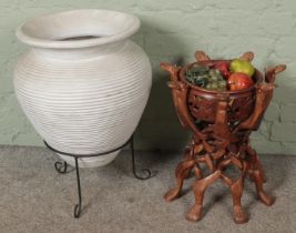 A large olive pot on stand along with a carved hardwood fruit bowl on folding camel stand.