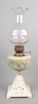 A oil lamp with cast iron painted base and glass shade.