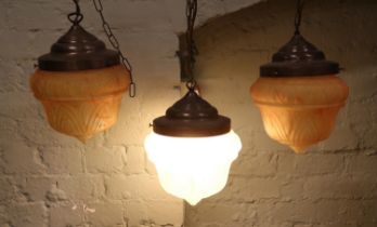 Three Art Deco hanging light fittings, with flamed amber coloured shades. One with power cable.