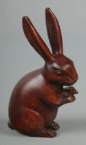 A hand carved hardwood netsuke of a rabbit, signed to base.