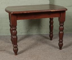 A stained pine table with turned supports. Height: 77cm, Width: 106cm, Depth: 79cm.