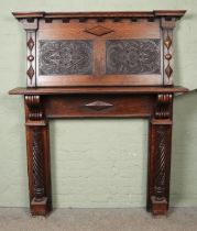 A two piece oak mantle surround, with heavily carved and twisted column supports. The upper