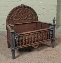 A nineteenth century cast iron and brass fire grate, with arched top and swag and bow decoration.