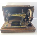 A vintage table top SINGER hand crank sewing machine in wooden case