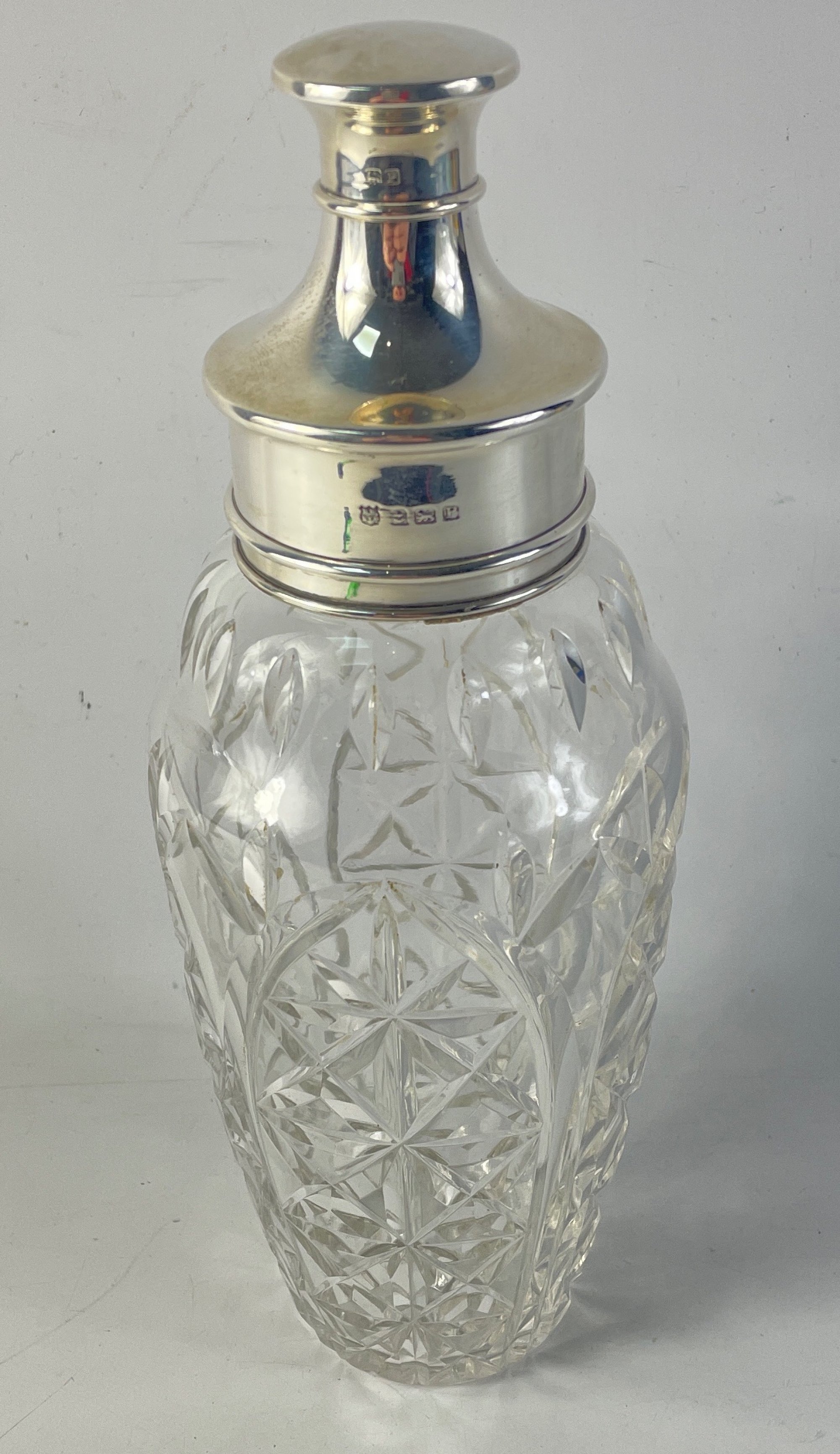 A nice quality cut-glass cocktail shaker with silver hallmarked collar, strainer and stopper,