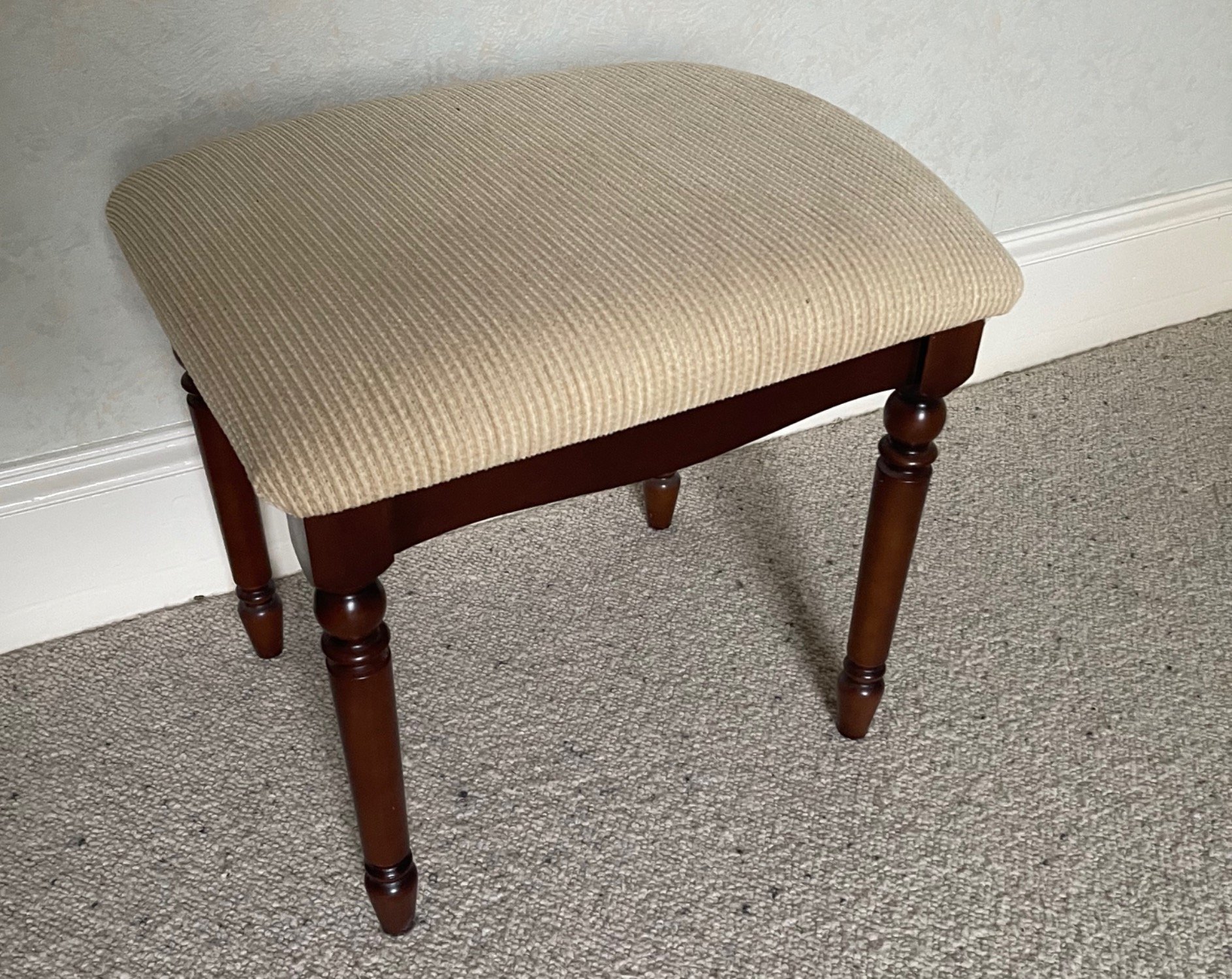 A dressing-table stool with cream upholstery