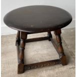 A round ERCOL inspired low occasional table in dark wood finish on four leg stretchered supports -