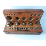 A vintage wooden box sold by AH BAIRD of Edinburgh, containing apothecary weights from 2g - 1kg (2