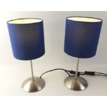 A pair of IKEA lamps with brushed metal stands and blue fabric shades