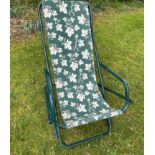 A handy garden relaxer fold-away seat with a leafy-green cloth fabric