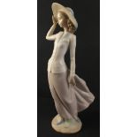 An attractively svelte LLADRO female figurine being blown by the wind