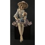 A beautiful LLADRO figurine of a young girl holding a doll in her lap sitting on a black plinth