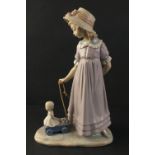 A charming LLADRO figurine depicting a young girl pulling a doll on a trolley