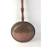 A copper and long wood handled antique bed warming pan