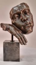 A bronze sculpture of a face on solid marble base